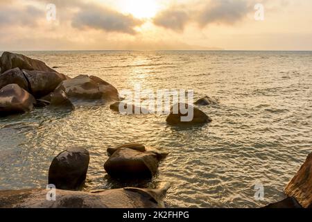 Tramonto attraverso le rocce in estate dall'Isola di Ilhabela Foto Stock