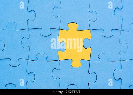 Il pezzo di puzzle giallo si distingue dalla folla Foto Stock
