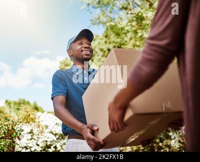 Consegna diretta a casa tua. Shot di un giovane addetto postale che consegna un pacchetto a una cliente femminile. Foto Stock