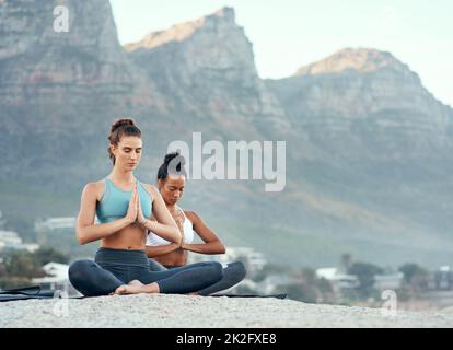 Lo yoga vi porta in un viaggio meraviglioso. Shot di due giovani donne sportive che praticano lo yoga all'aperto. Foto Stock