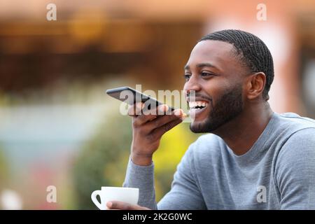 Uomo felice con la pelle nera che dettano il messaggio sul telefono Foto Stock