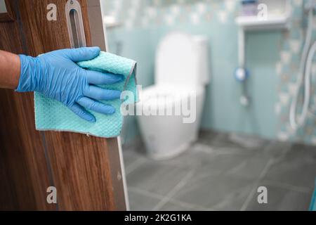 Pulizia porta toliet manico in bagno con alcool e panno morbido in ufficio e a casa per proteggere il cocid 19 coronavirus Foto Stock