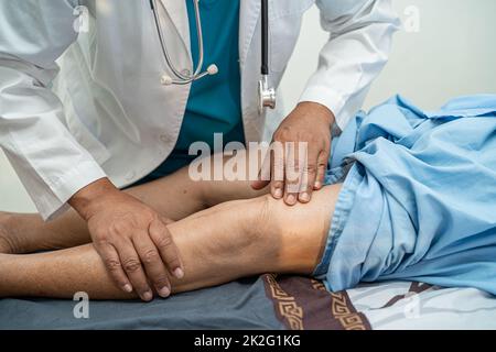 Medico asiatico fisioterapista esame, massaggio e trattamento ginocchio e gamba di paziente anziano in ospedale medico ambulatorio ortopedist infermiere. Foto Stock