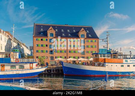 71 Nyhavn Hotel, sul canale Nyhavn, che si trova in un vecchio magazzino di mattoni e diverse navi di fronte ad esso. Copenaghen, Danimarca Foto Stock