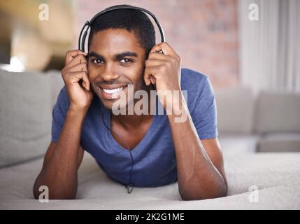 Ascoltare i miei brani preferiti, un bel giovane che si rilassa a casa con un po' di musica. Foto Stock