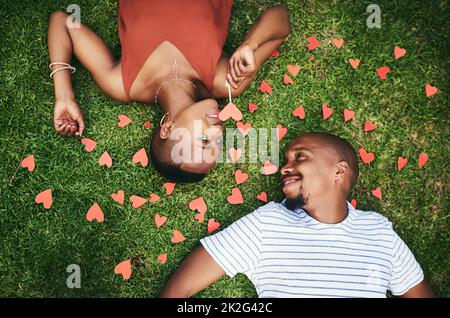 Quando ti guardo, tutto quello che vedo è amore. Scatto ritagliato di una giovane coppia sdraiata sul prato all'esterno. Foto Stock