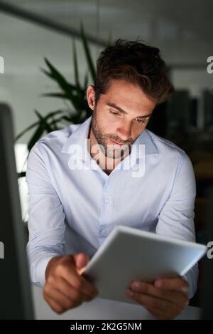 Mettendo nelle ore per realizzare il successo. Shot di un giovane uomo d'affari che lavora tardi in ufficio. Foto Stock