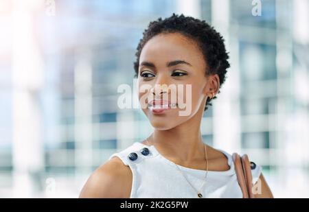 Ive solo appena iniziato.... Scatto corto di una giovane donna d'affari attraente che osserva pensieroso mentre si levano in piedi in un ufficio moderno. Foto Stock