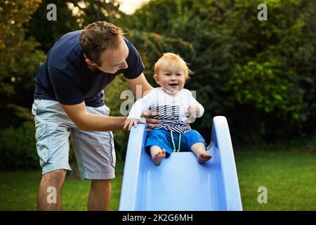 Daddys mi aiuta a scorrere. Sparato di un adorabile ragazzino e suo padre che gioca nel cortile. Foto Stock