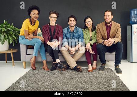 Incontra il miglior team dell'azienda. Ritratto di un gruppo di giovani creativi seduti insieme su un divano in un ufficio. Foto Stock