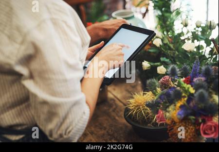 Questa app mi aiuta a tenere traccia di tutte le mie scorte. Scatto ritagliato di un fiorista irriconoscibile utilizzando un tablet digitale mentre lavora all'interno del suo vivaio vegetale. Foto Stock