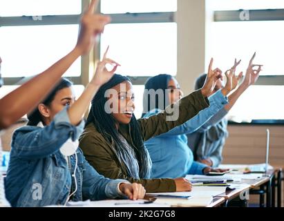 Theyve prestava attenzione. Scatto ritagliato di un gruppo di studenti universitari seduti con le mani sollevate in classe. Foto Stock