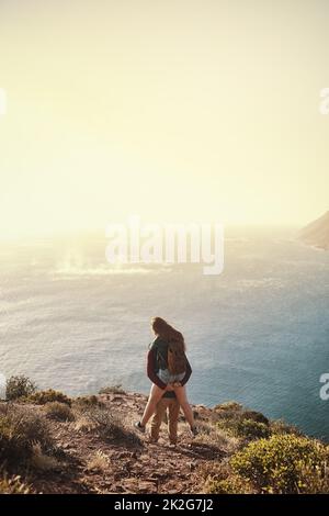 Potete vedere da dietro là. Dietro l'immagine di un giovane uomo che sostiene la sua ragazza durante la loro escursione in montagna. Foto Stock