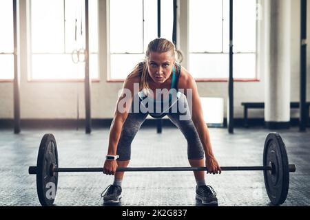 Trova il combattente all'interno e continua a sfidarti. Shot di una giovane donna sportiva che solleva pesi in palestra. Foto Stock