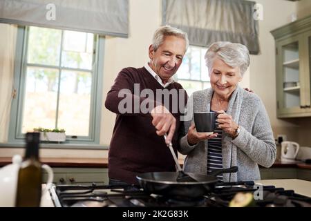 Lasciate che tutta la cucina mi sia lasciata. Shot di una coppia affettuosa senior che cucinano insieme nella loro cucina a casa. Foto Stock