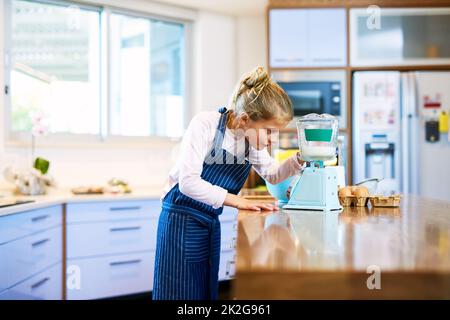 Ottenere gli ingredienti alla misura esatta. Scatto corto di una bambina che misura gli ingredienti su una scala mentre cuoce a casa. Foto Stock