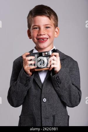 Giovane Weegee. Studio girato di un ragazzo in un vecchio vestito con una fotocamera vintage. Foto Stock