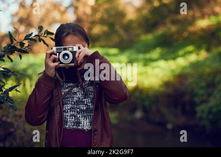 È come vedere il mondo attraverso occhi nuovi. Scatto di una ragazza giovane che scatta foto con una macchina fotografica vintage all'aperto. Foto Stock