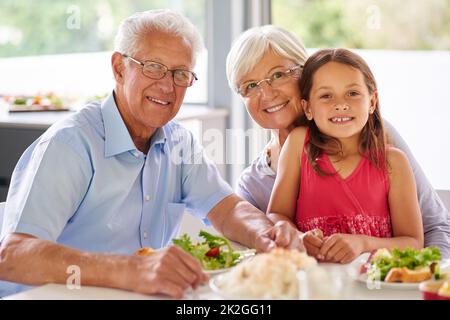 Mangiare bene li ha tenuti spritely. Ritratto di una bambina a pranzo con i suoi nonni. Foto Stock