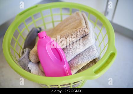 Tenete puliti gli asciugamani. Shot di una bottiglia di detergente e asciugamani piegati in un cestino per il bucato. Foto Stock