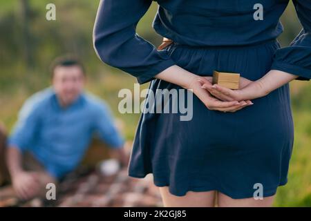 Shes ha accucchiato il coraggio di schioccare la domanda invece. Vista posteriore di una donna che sta per proporre al suo ragazzo con un anello di fidanzamento in una scatola. Foto Stock