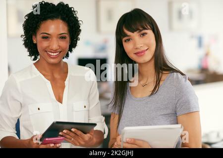 Cosa possiamo progettare per voi oggi. Ritratto di due giovani donne d'affari fiduciose che lavorano insieme in un ufficio moderno. Foto Stock