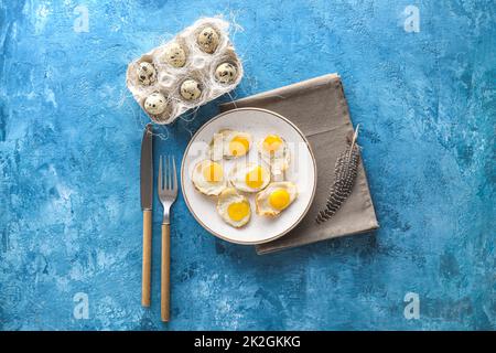 Piatto con gustose uova di quaglia fritte su sfondo colorato Foto Stock