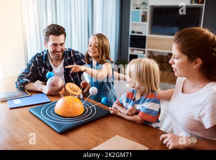 Viaggiavano insieme attraverso l'universo. Scatto di una bella giovane famiglia che lavora insieme su un progetto scientifico a casa. Foto Stock