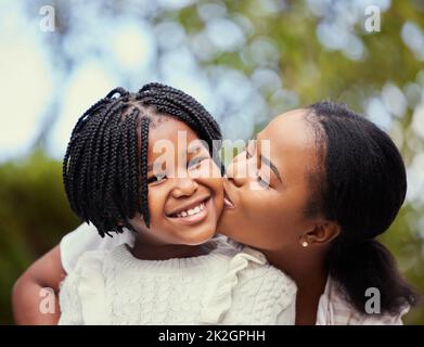 Avere una madre significa avere un migliore amico per la vita. Scatto di una giovane madre che dà alla figlia un bacio in natura. Foto Stock