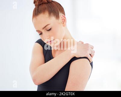 In qualsiasi sport possono verificarsi lesioni e il balletto non fa eccezione. Colpo di una giovane ballerina che soffre di dolore alla spalla. Foto Stock