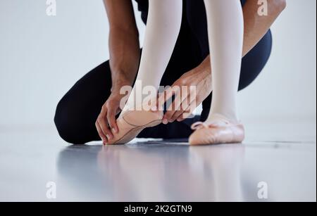 Imparare i passi uno alla volta. Primo piano di un insegnante di balletto che assiste uno studente con la sua posizione in uno studio di danza. Foto Stock