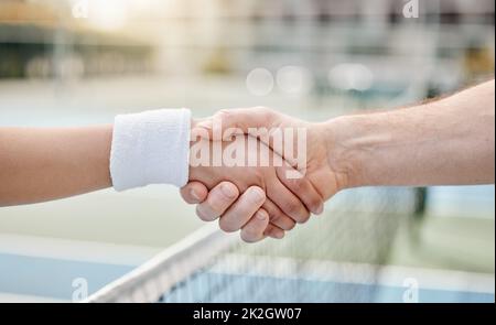 Bel gioco. Scatto corto di due giocatori di tennis irriconoscibili che scuotono le mani mentre si alza fuori su un campo. Foto Stock