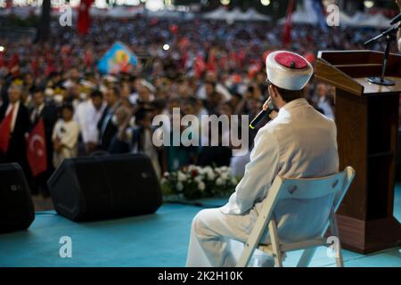 Smirne, Turchia - 15 luglio 2022: 15 luglio Giornata della democrazia in Turchia Smirne. Vista posteriore di un imam con microfono sul palco. Foto Stock