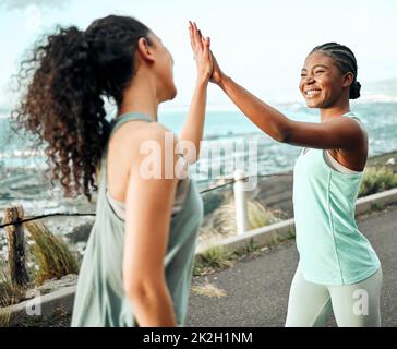 Abbiamo raggiunto un altro obiettivo di fitness. Sparato di due giovani donne che si donano un alto cinque mentre si allenano in natura. Foto Stock