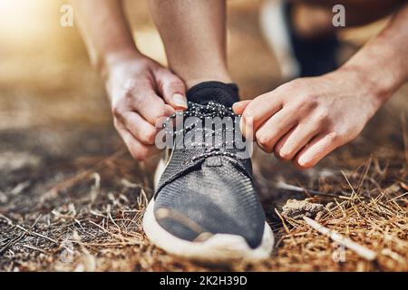 Bello e stretto. Oggi non inciamperò. Sparato di una persona giovane che lega le loro scarpe prima di andare per una corsa all'aperto. Foto Stock