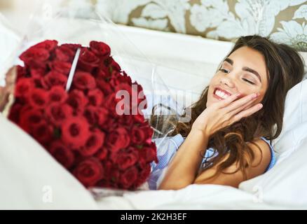 Che sorpresa. Scatto corto di una giovane donna attraente che guarda sorpreso dopo il risveglio fino ad un bouquet di rose. Foto Stock