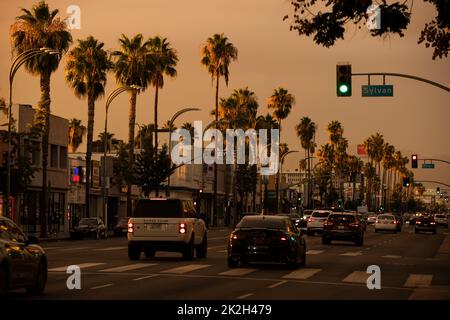 Van Nuys, California, USA - 11 settembre 2022: Il tramonto illumina le palme e il traffico lungo Van Nuys Blvd nel cuore del centro. Foto Stock