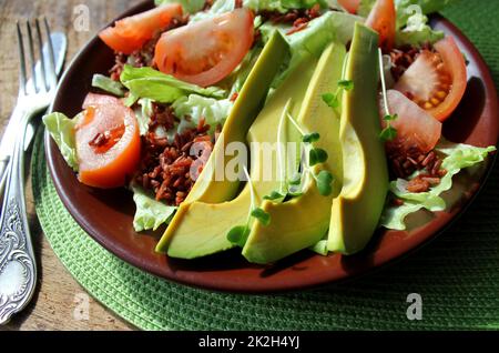 Deliziosa insalata verde fresca con pomodoro, avocado e riso rosso Foto Stock