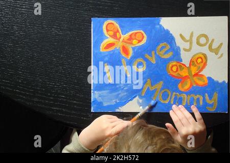 mano di un bambino che dipinge un'immagine per la mamma Foto Stock