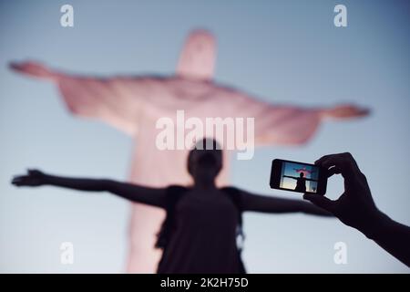 Cattura l'attimo. Un tiro corto di una donna che imita la posa di Cristo Redentore a Rio. Foto Stock