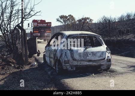 Izmir, Turchia - 23 luglio 2022: Vista posteriore di auto bruciata con un camion da fuoco di fronte ad esso dopo l'incendio della foresta a Derya Site Seferihisar Izmir Turchia Foto Stock