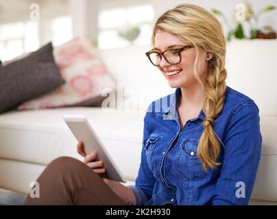 Connettersi con i suoi amici online. Scatto corto di una giovane donna usando la sua tavoletta a casa. Foto Stock