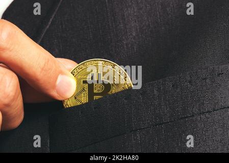 Smirne, Turchia - 11 agosto 2022: Mano di un uomo d'affari che tiene un bitcoin da mettere in tasca. Foto Stock