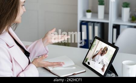 Teleconferenza aziendale. Chat Web. Webcast professionale. Diversi colleghi discutono di un progetto di successo online sullo schermo del tablet nell'ufficio digitale. Foto Stock
