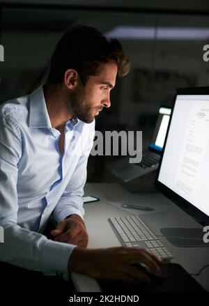 Mettendo nelle ore per realizzare il successo. Shot di un giovane uomo d'affari che lavora tardi in ufficio. Foto Stock