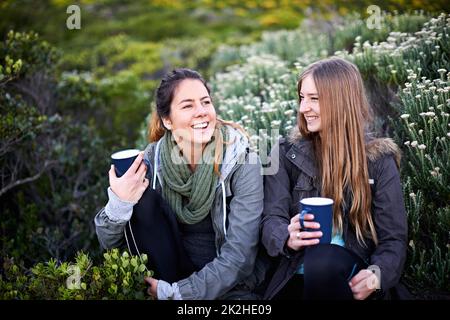 Risate in montagna. Scatto di due giovani donne attraenti godendo di bevande calde durante le escursioni. Foto Stock