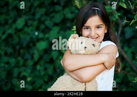 Lo amo così tanto. Scatto di una bambina in piedi fuori con il suo orsacchiotto. Foto Stock