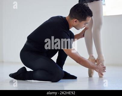 Dovete stare così. Primo piano di un insegnante di balletto che assiste uno studente con la sua posizione in uno studio di danza. Foto Stock