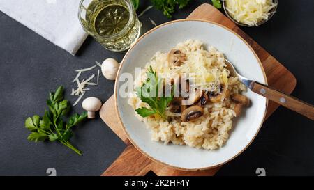 Risotto ai funghi guarnito con prezzemolo e parmigiano. Foto Stock