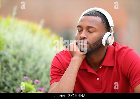 Uomo con pelle nera che riposa ascoltando musica Foto Stock